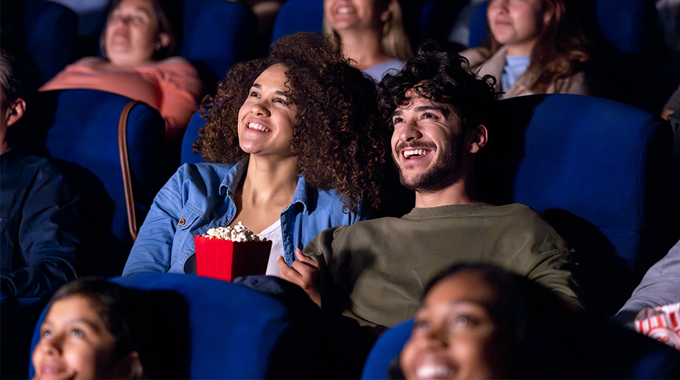 Happy couple watching a movie at the theatre and smiling